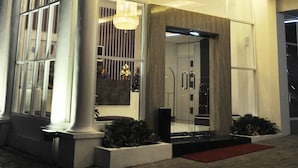 L’entrée d’un hôtel, avec une enseigne « VIO » bien visible, de grandes colonnes et un lustre moderne.
