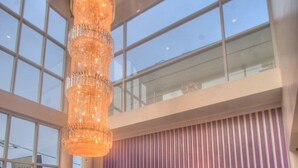 Un espace d’accueil au design moderne, agrémenté d’un grand lustre, d’un comptoir de réception et d’un téléviseur fixé au mur.