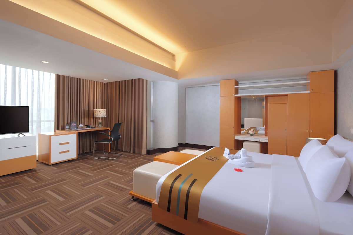 A hotel room with a bed, desk, chair, TV, and wardrobe.
