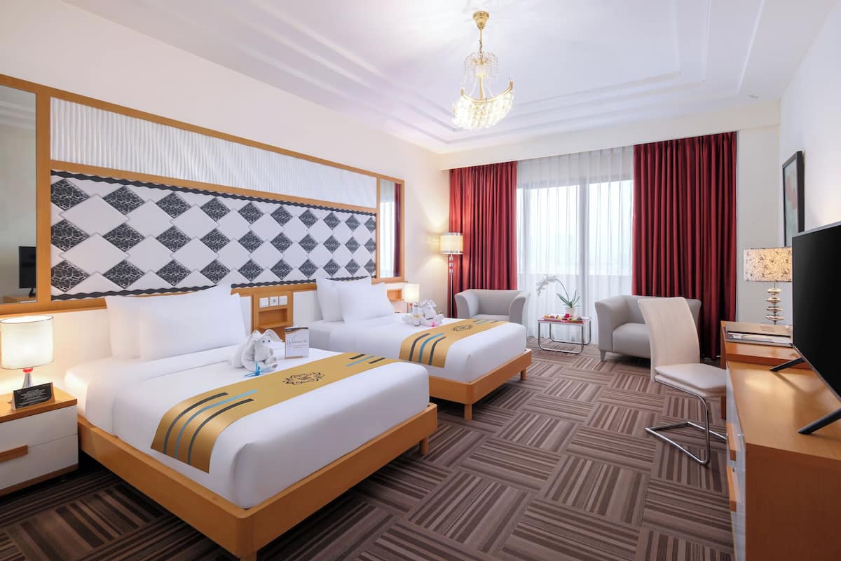 A hotel room with two beds, a desk, a TV, a chair, and a large mirror.