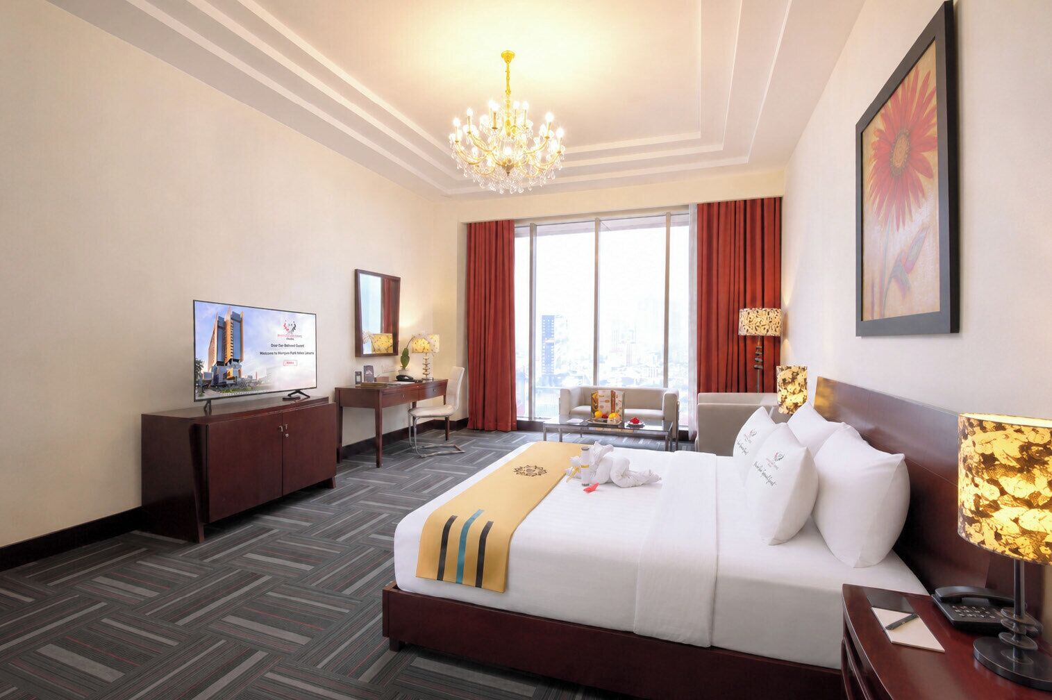 Habitación de hotel con cama, escritorio, silla, televisor y un amplio ventanal con cortinas.