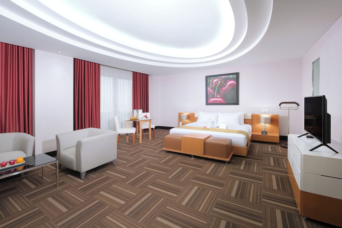 A modern hotel room with a bed, a sofa, a desk, and a television.