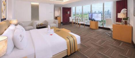 A hotel room with a large bed, a desk, a TV, and a city view.