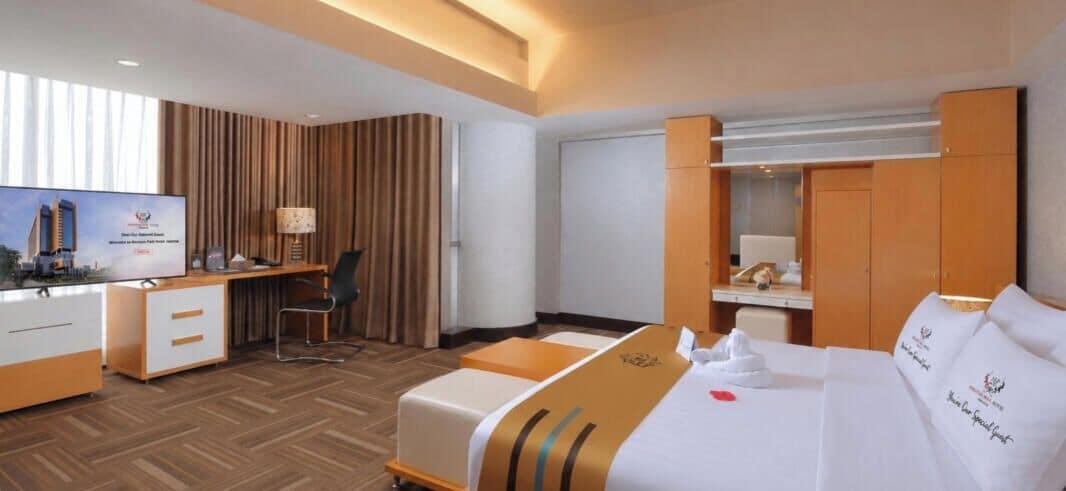 A hotel room with a bed, desk, chair, television, and wardrobe.