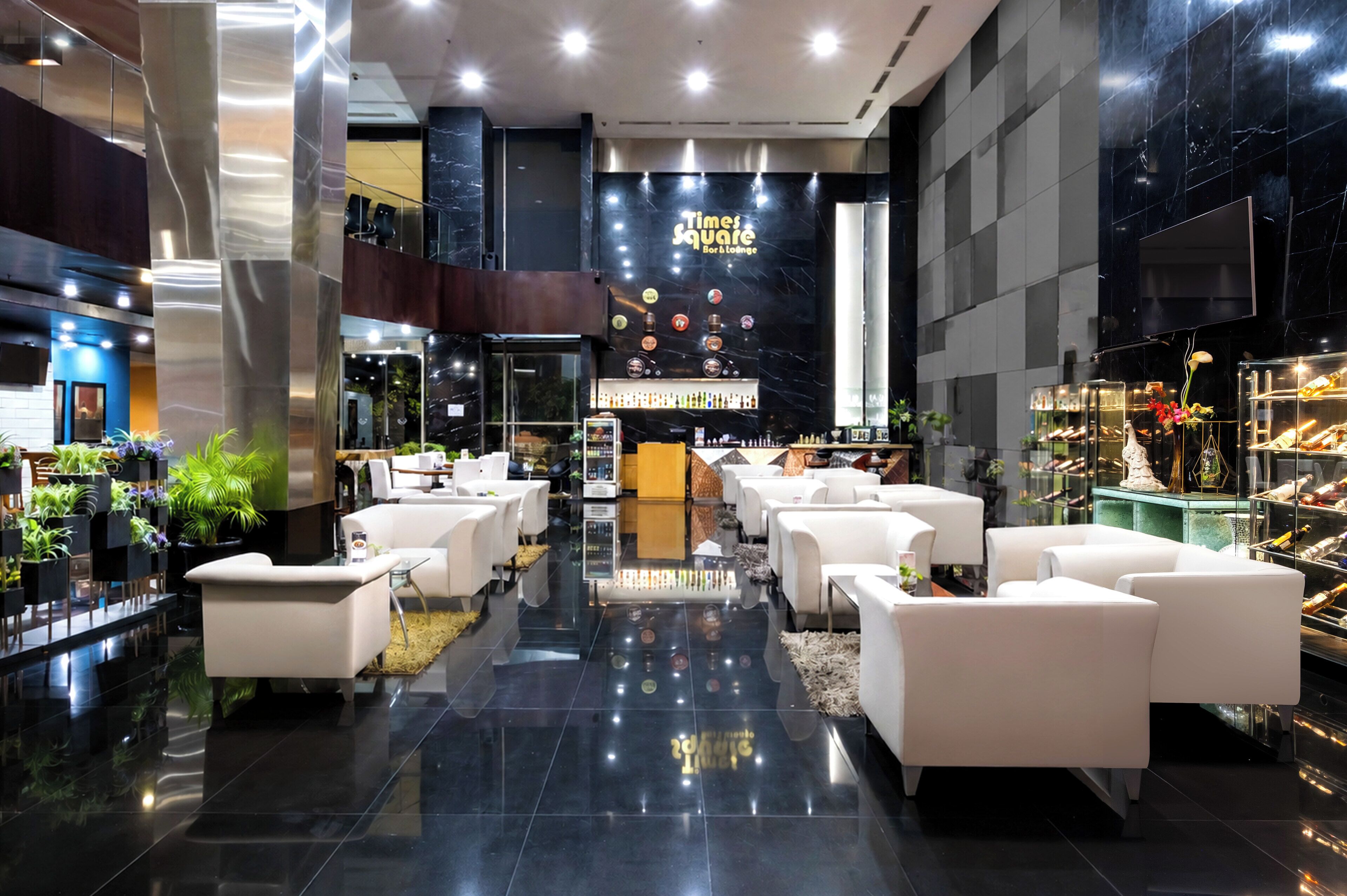 A modern lobby with a bar area, seating arrangements, and a display of bottles.