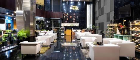 A modern lobby with a bar area, seating arrangements, and a display of bottles.