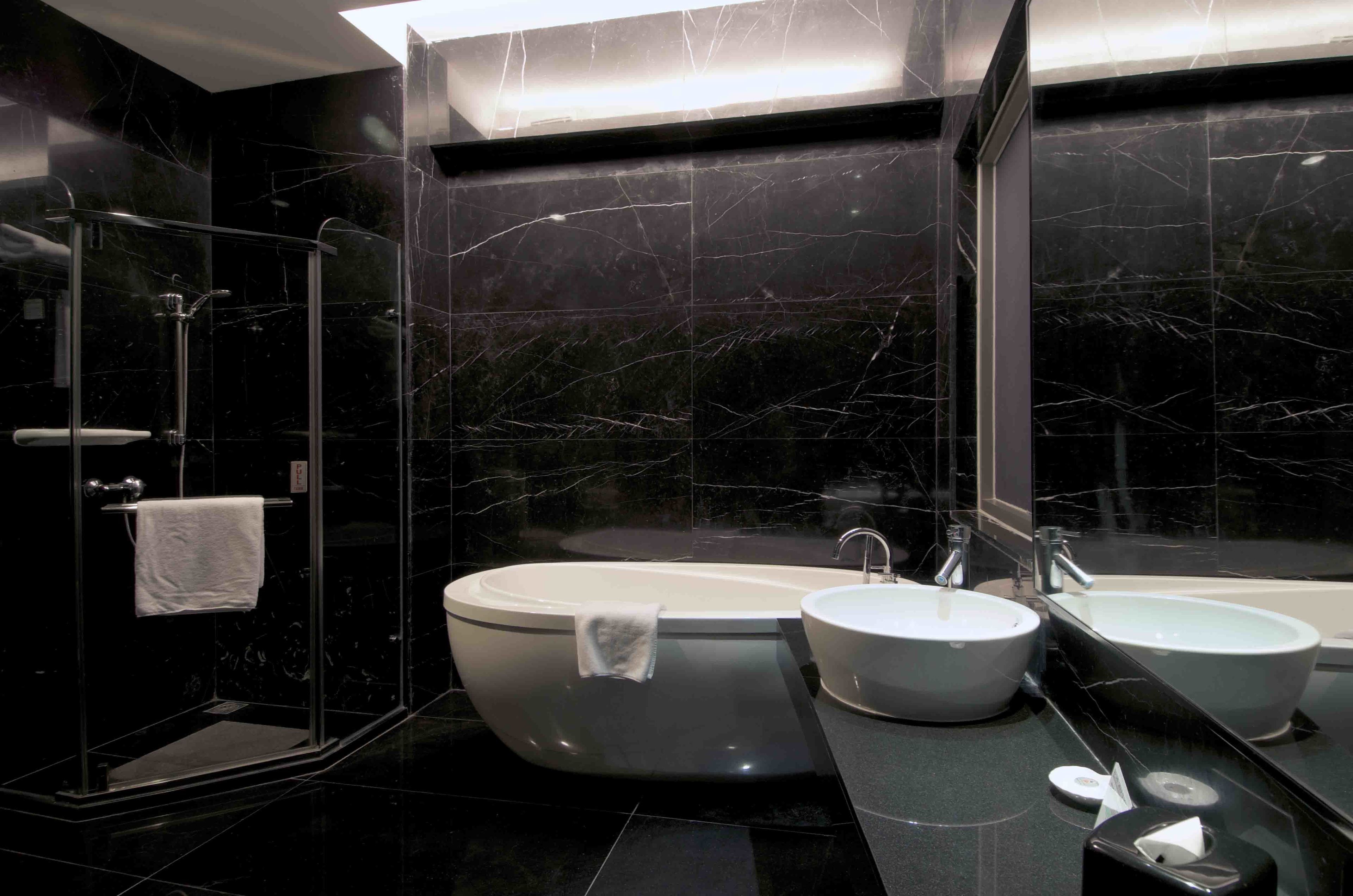 A modern bathroom with a freestanding bathtub, two sinks, and a glass-enclosed shower.