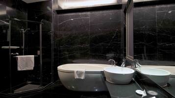 A modern bathroom with a freestanding bathtub, two sinks, and a glass-enclosed shower.