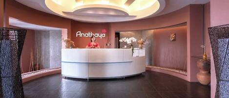 A reception area with a curved reception desk, a wall-mounted sign reading 'Anathaya,' and a modern ceiling design.