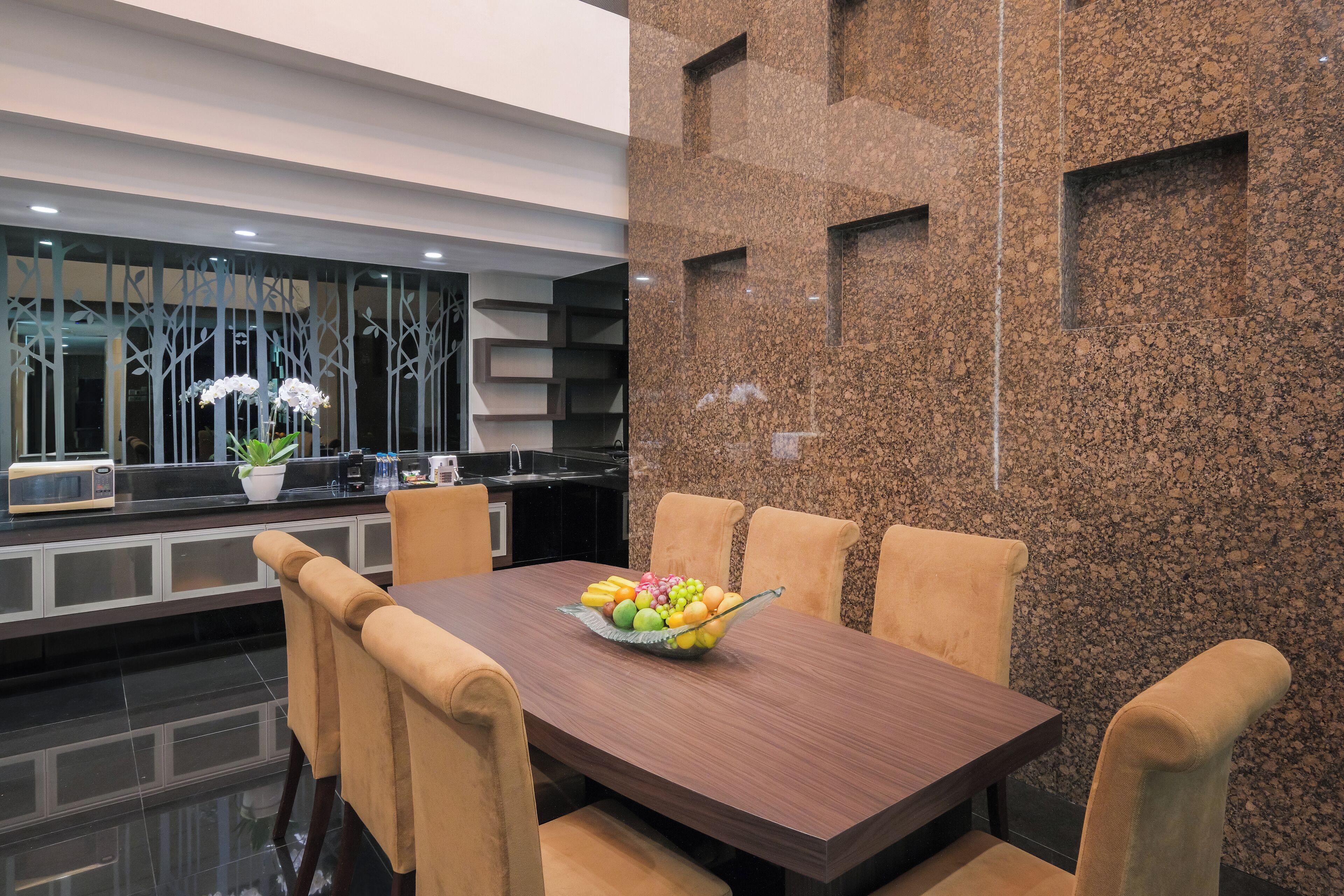 A modern dining area with a wooden table, beige chairs, and a fruit bowl.