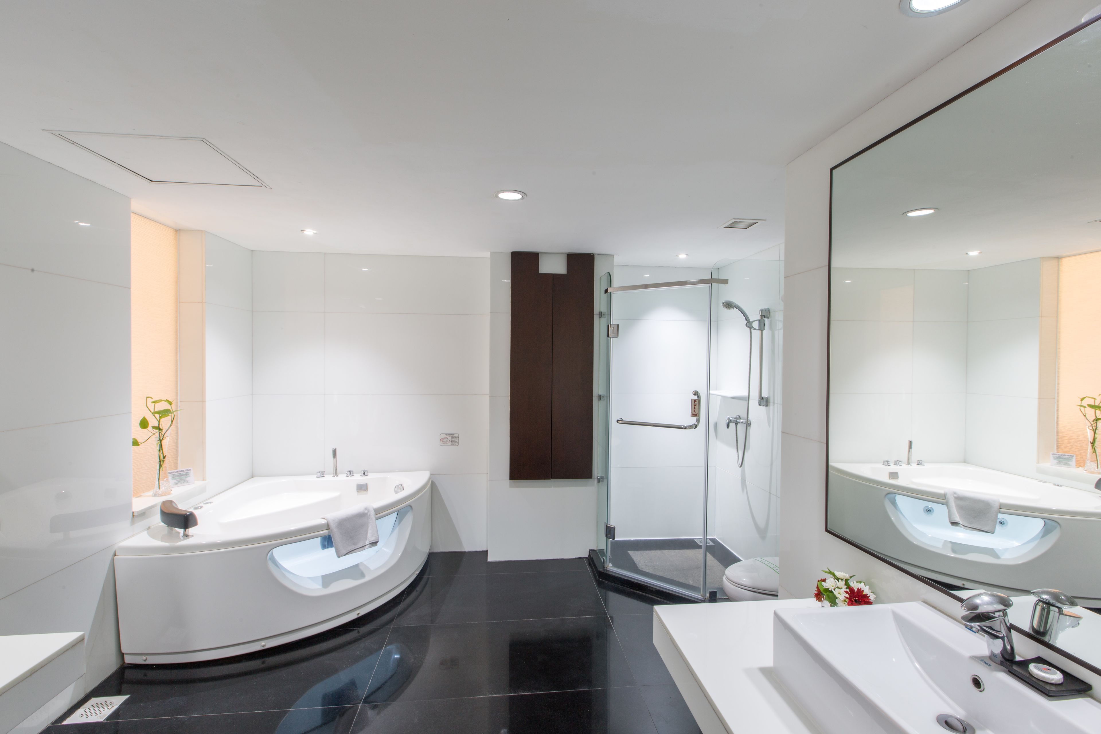 Un baño moderno con un espejo grande, dos lavamanos, una ducha y cabina de ducha con paredes de vidrio.