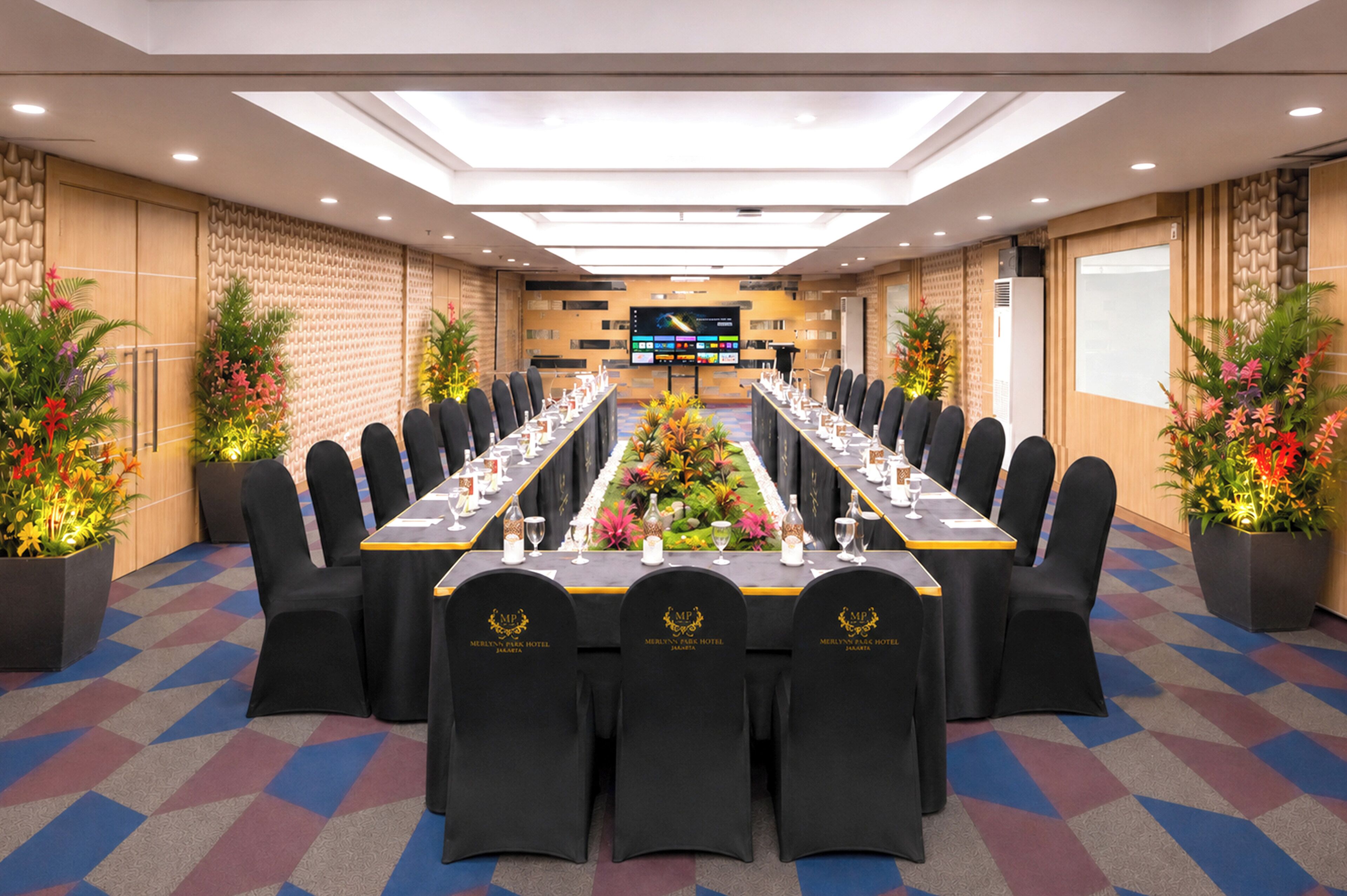 Une salle de conférence équipée d’une longue table, de chaises et d’un grand écran.