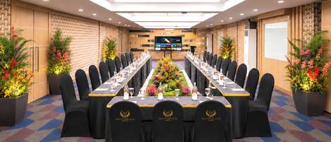 A conference room with a long table, chairs, and a large screen.