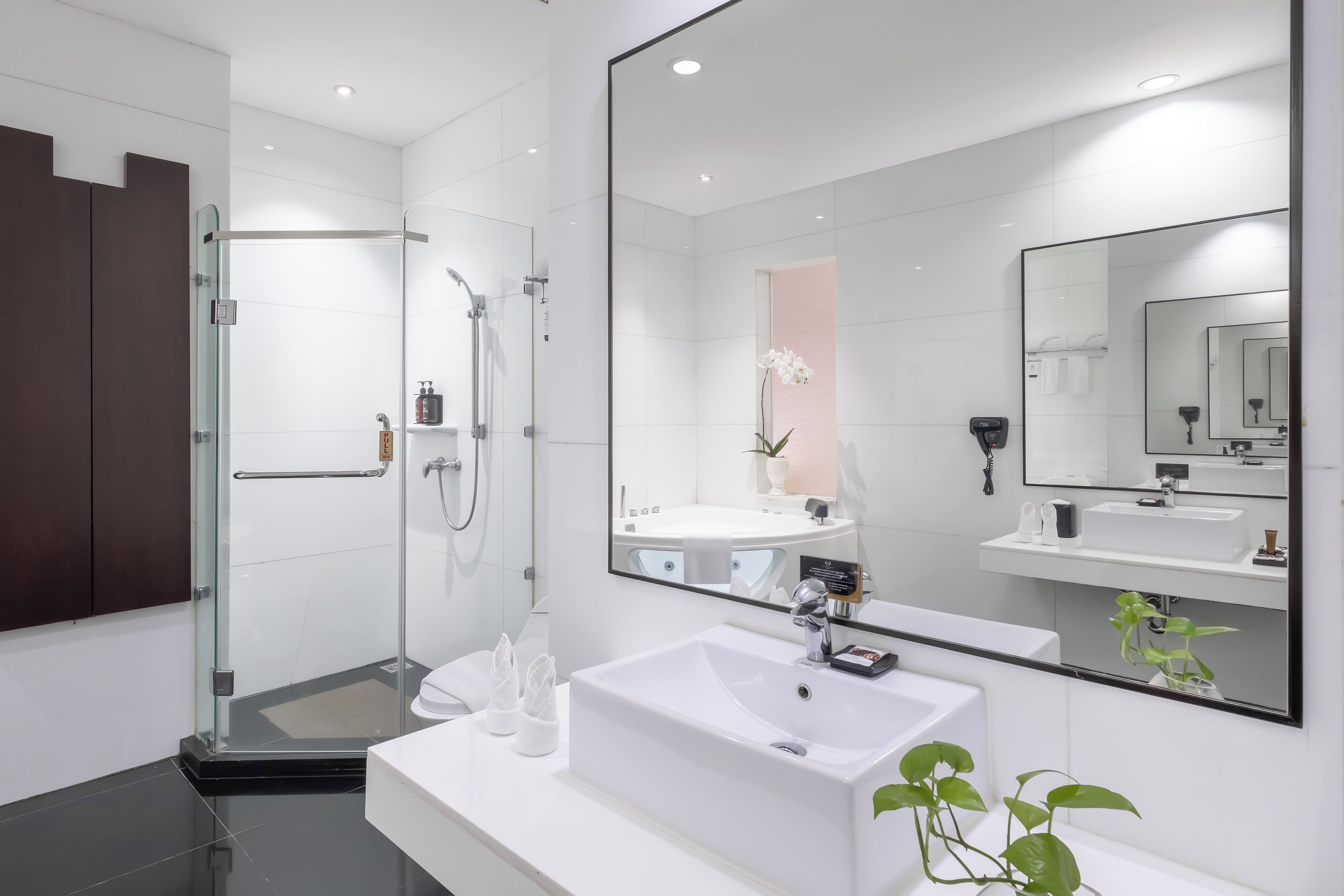 Un baño moderno con ducha de vidrio, lavamanos blanco y espejo grande.