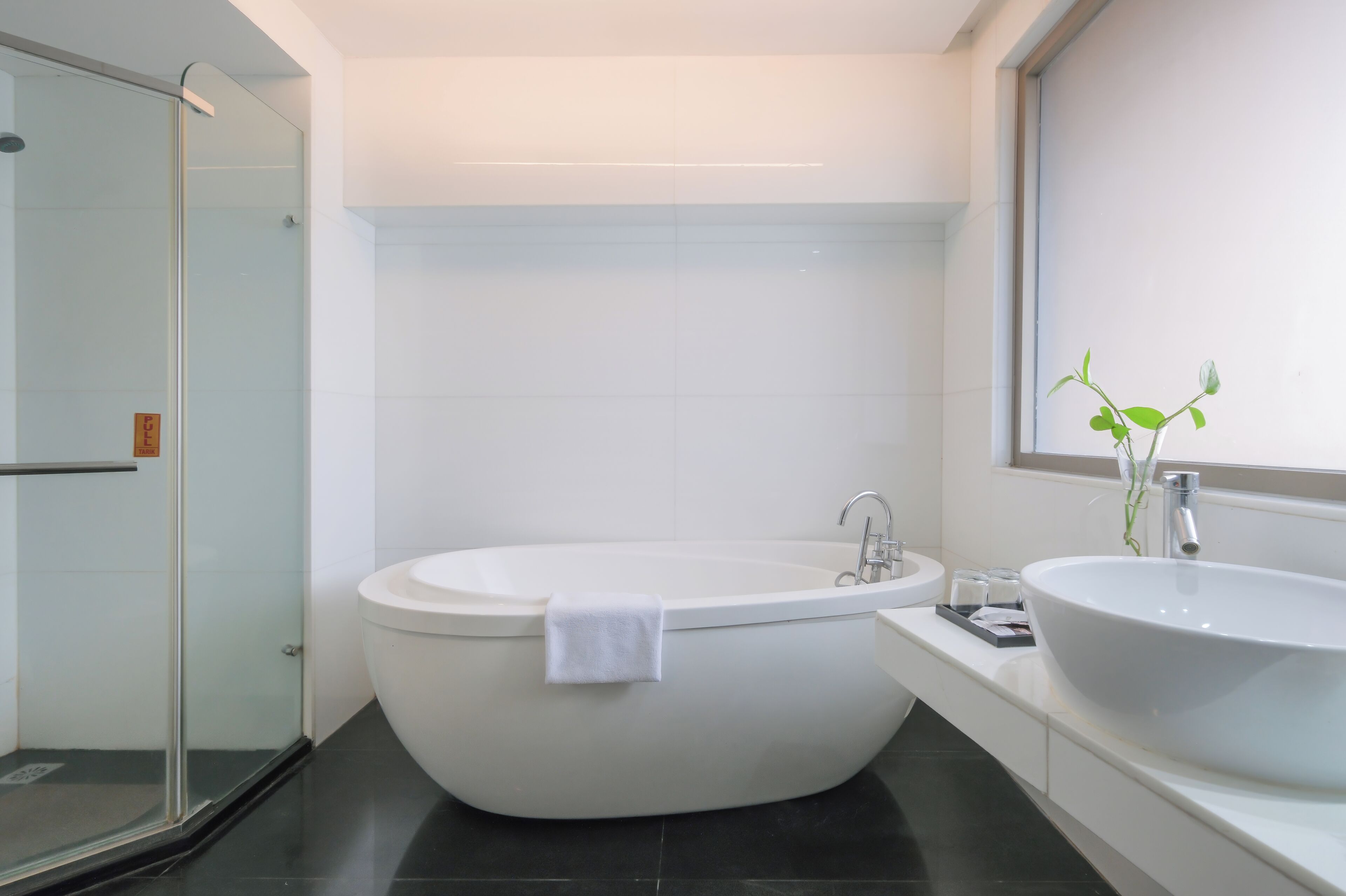 Un baño moderno con una bañera independiente, cabina de ducha de vidrio y un lavamanos grande.