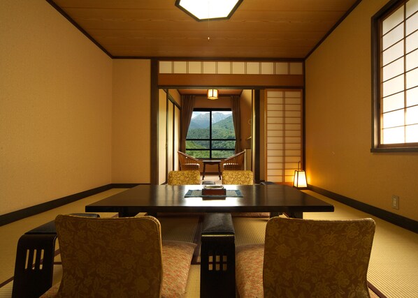 Una habitación tradicional japonesa con suelo de tatami, una mesa baja y dos sillas.