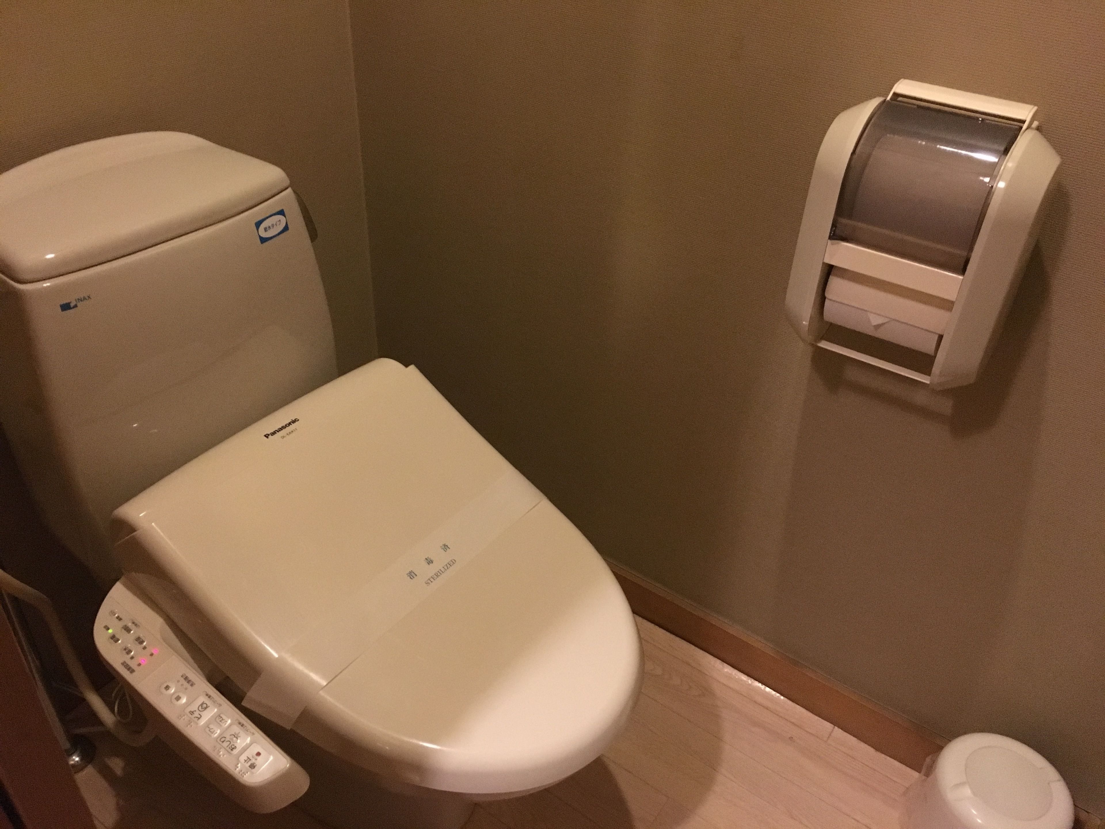 Des toilettes modernes dotées d’un panneau de commande, d’un distributeur de papier toilette et d’un accessoire de type bidet.