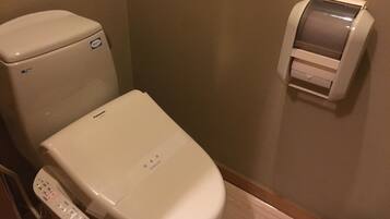 Des toilettes modernes dotées d’un panneau de commande, d’un distributeur de papier toilette et d’un accessoire de type bidet.