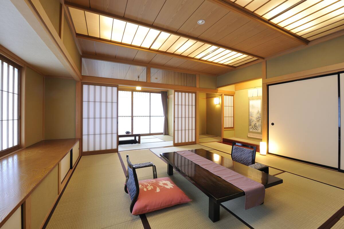 A traditional Japanese room with tatami flooring, a low table, a bench, and sliding doors.