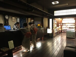 A reception area with a wooden floor, a reception desk, a computer, and a clock on the wall.