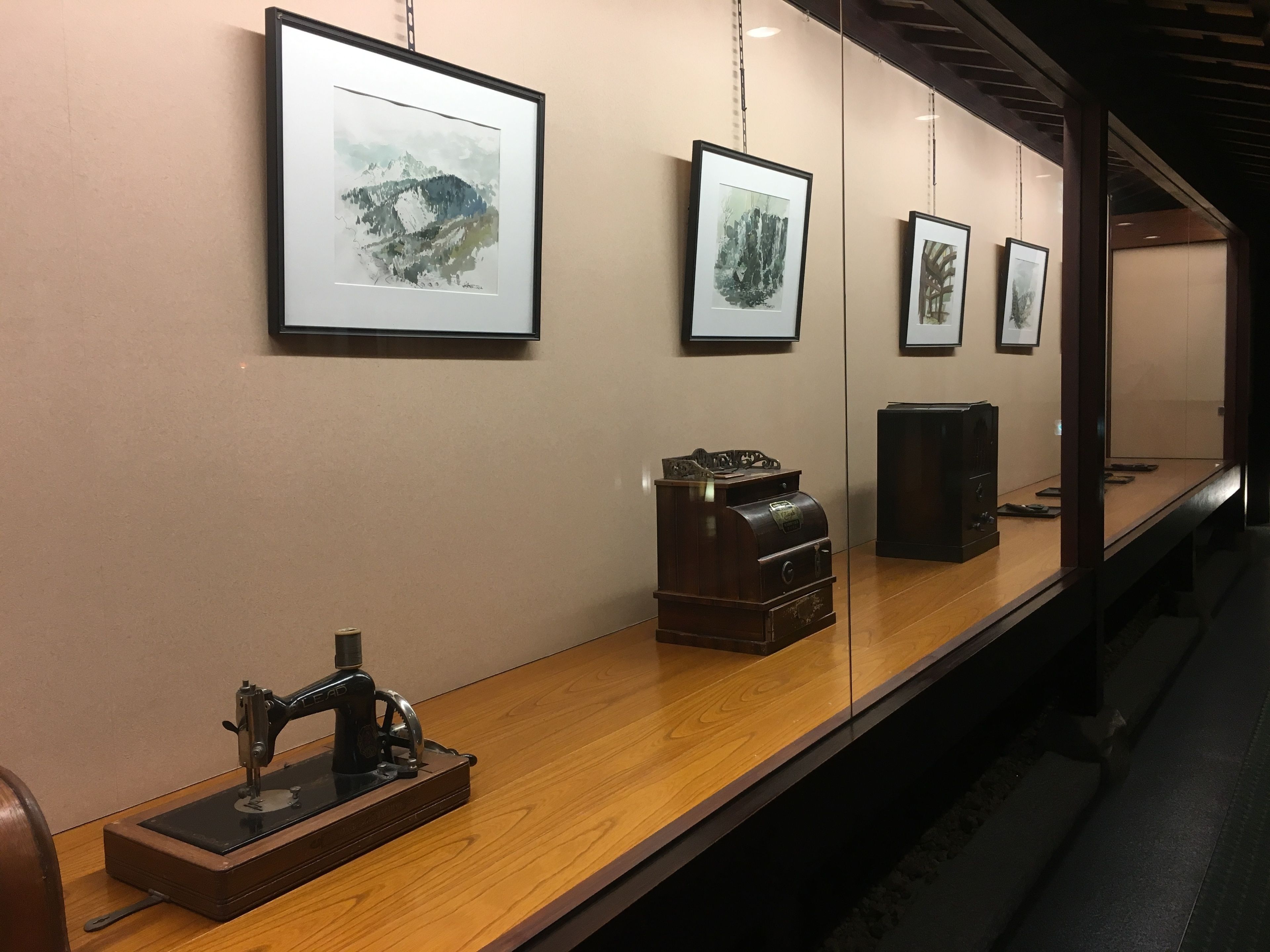 A gallery wall with framed artworks and a vintage sewing machine on display.