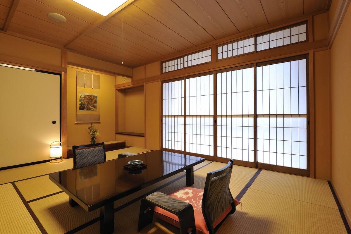 A traditional Japanese room with tatami flooring, a low table, and sliding doors.