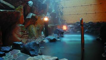 A serene indoor water feature with a stone pathway, illuminated lights, and a bamboo wall.