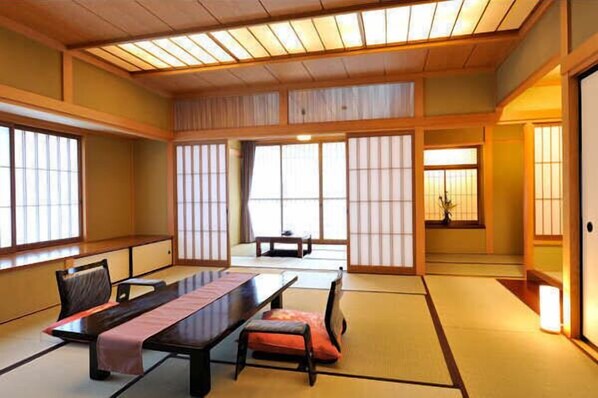 A traditional Japanese room with tatami flooring, sliding doors, and a low table with cushions. - Hodakaso Sangetsu (Takayama)