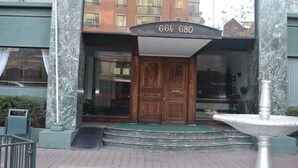 Une entrée d’immeuble avec une façade en marbre, une porte en bois et un panneau indiquant le numéro de l’immeble au-dessus.