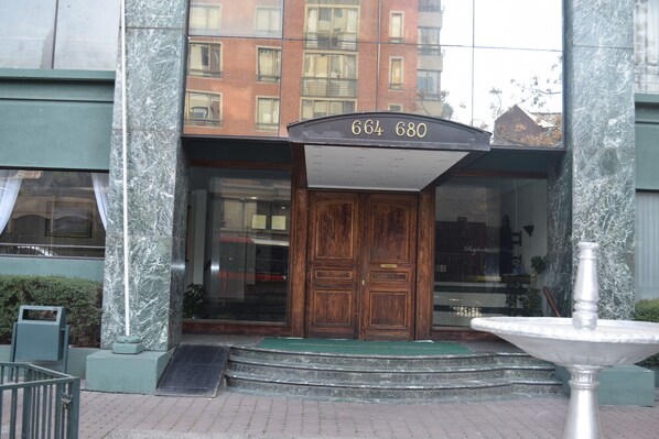 Une entrée d’immeuble avec une façade en marbre, une porte en bois et un panneau indiquant le numéro de l’immeble au-dessus.