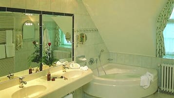 Un baño con una bañera grande, un lavamanos y un espejo.