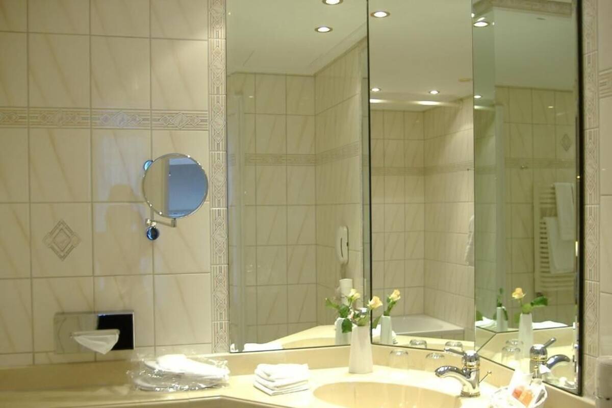 Een badkamer met een grote spiegel, een wastafel en een badkamermeubel.