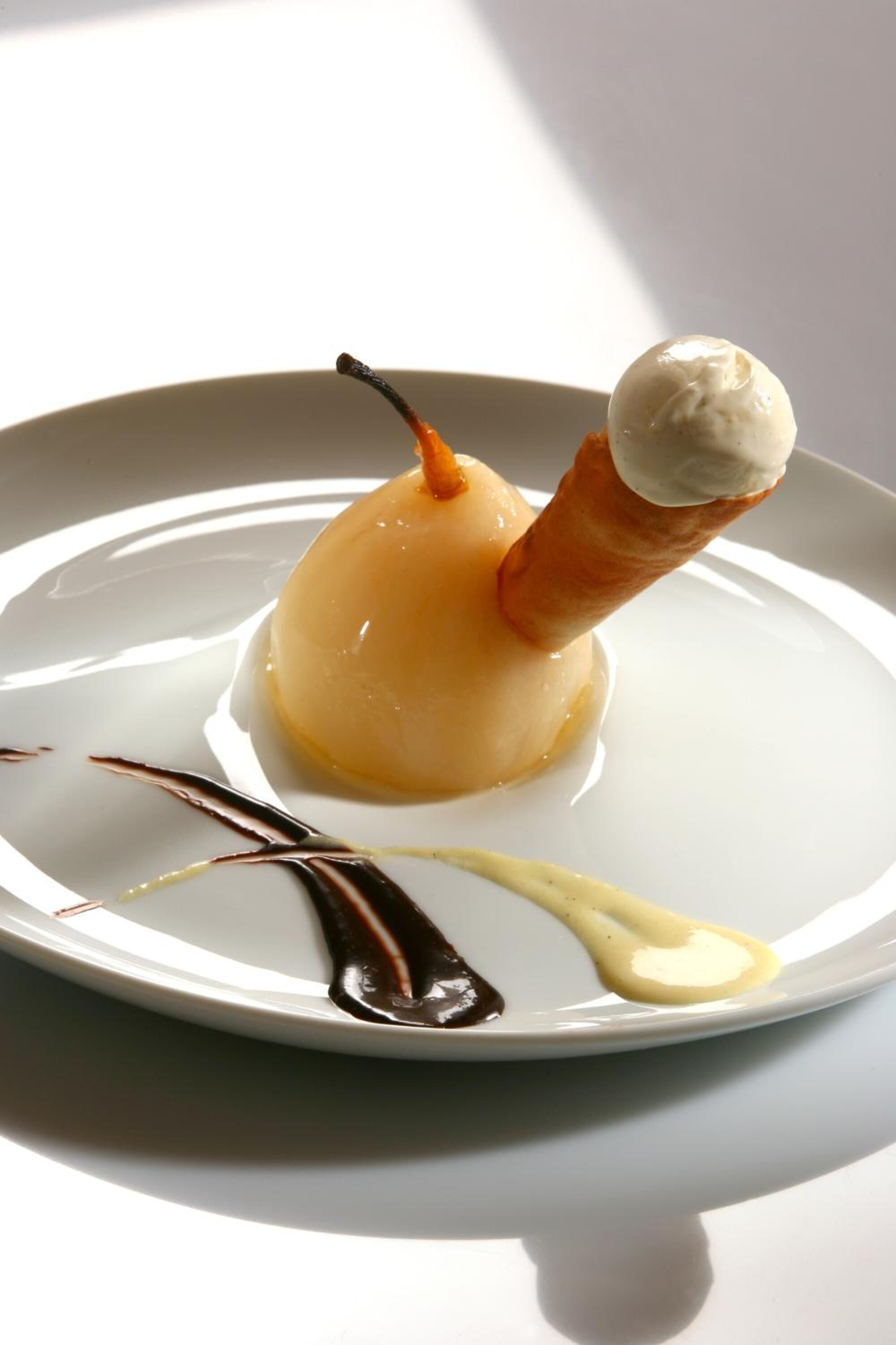 Ein Dessert auf einem Teller mit Schokoladen- und Vanillesauce.