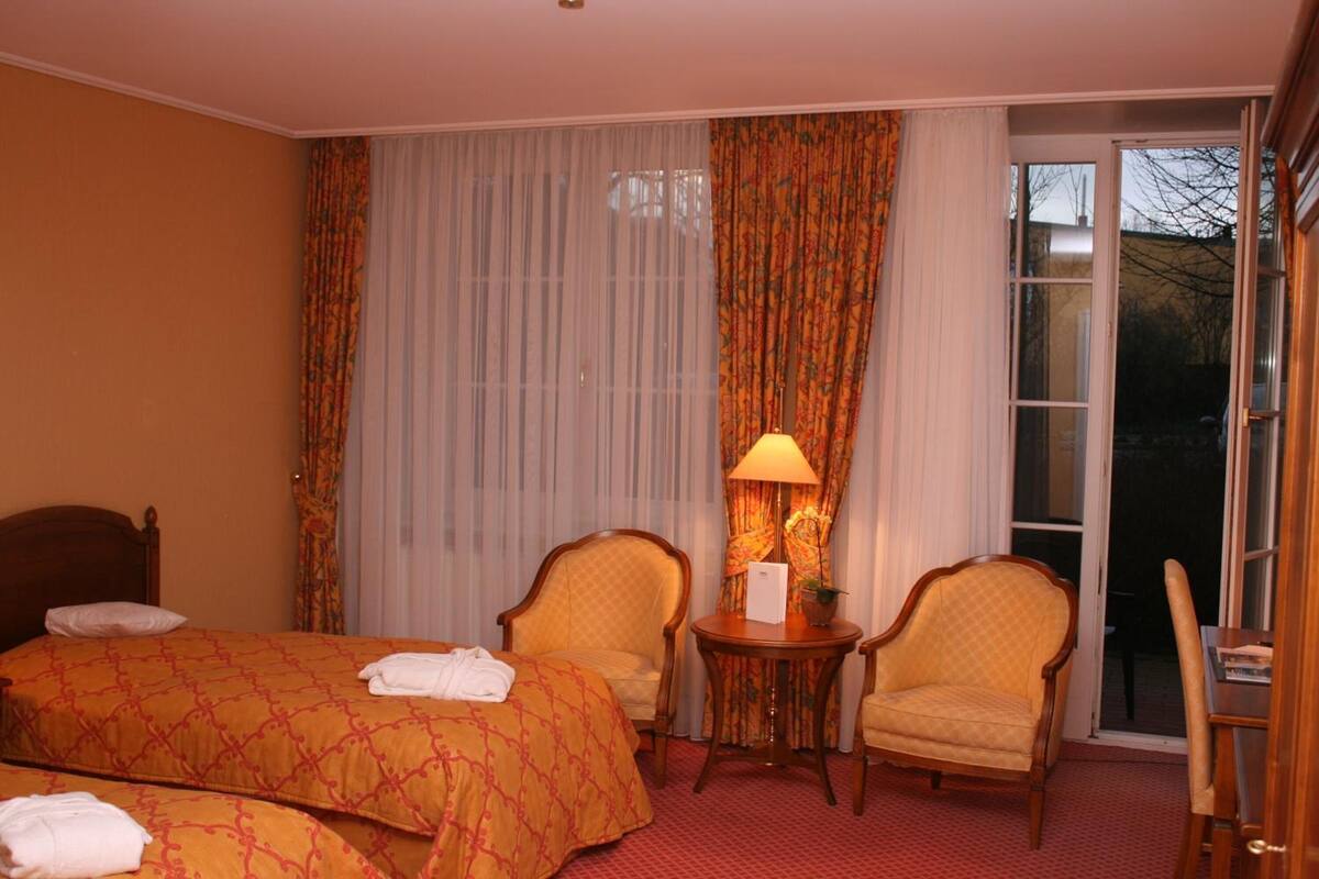 Hotelkamer met twee bedden, een zithoek met stoelen, een tafel en uitzicht door een glazen deur.