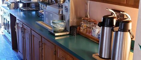 A kitchen with wooden cabinets, a green countertop, a coffee machine, and stainless steel water dispensers.