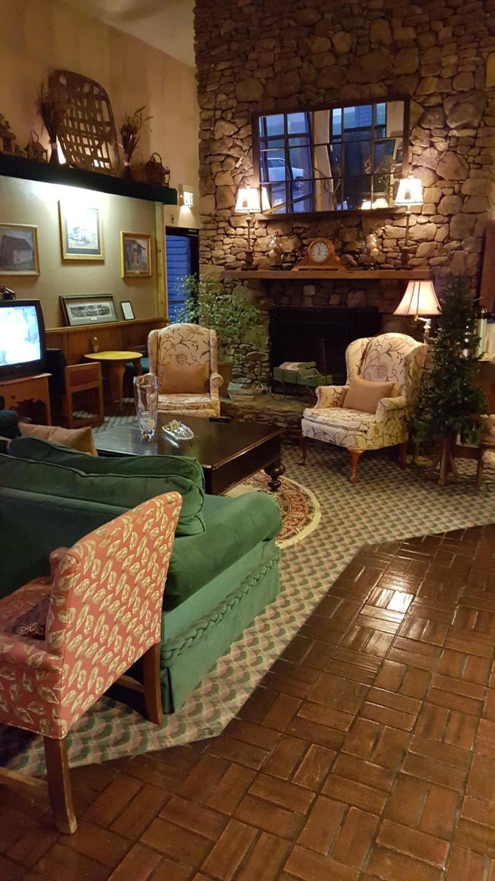 Un salon chaleureux avec une cheminée en pierre, des fauteuils confortables et un téléviseur.