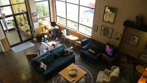A spacious living area with a large window, a sofa set, a coffee table, and a television.