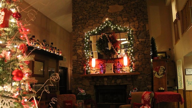 A cozy living room with a stone fireplace, a Christmas tree, and festive decorations.