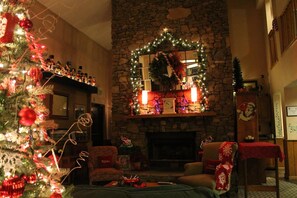 Una sala de estar acogedora con una chimenea de piedra, un árbol de Navidad y decoraciones festivas.