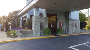 A building with a stone facade, a red door, and a covered entrance.