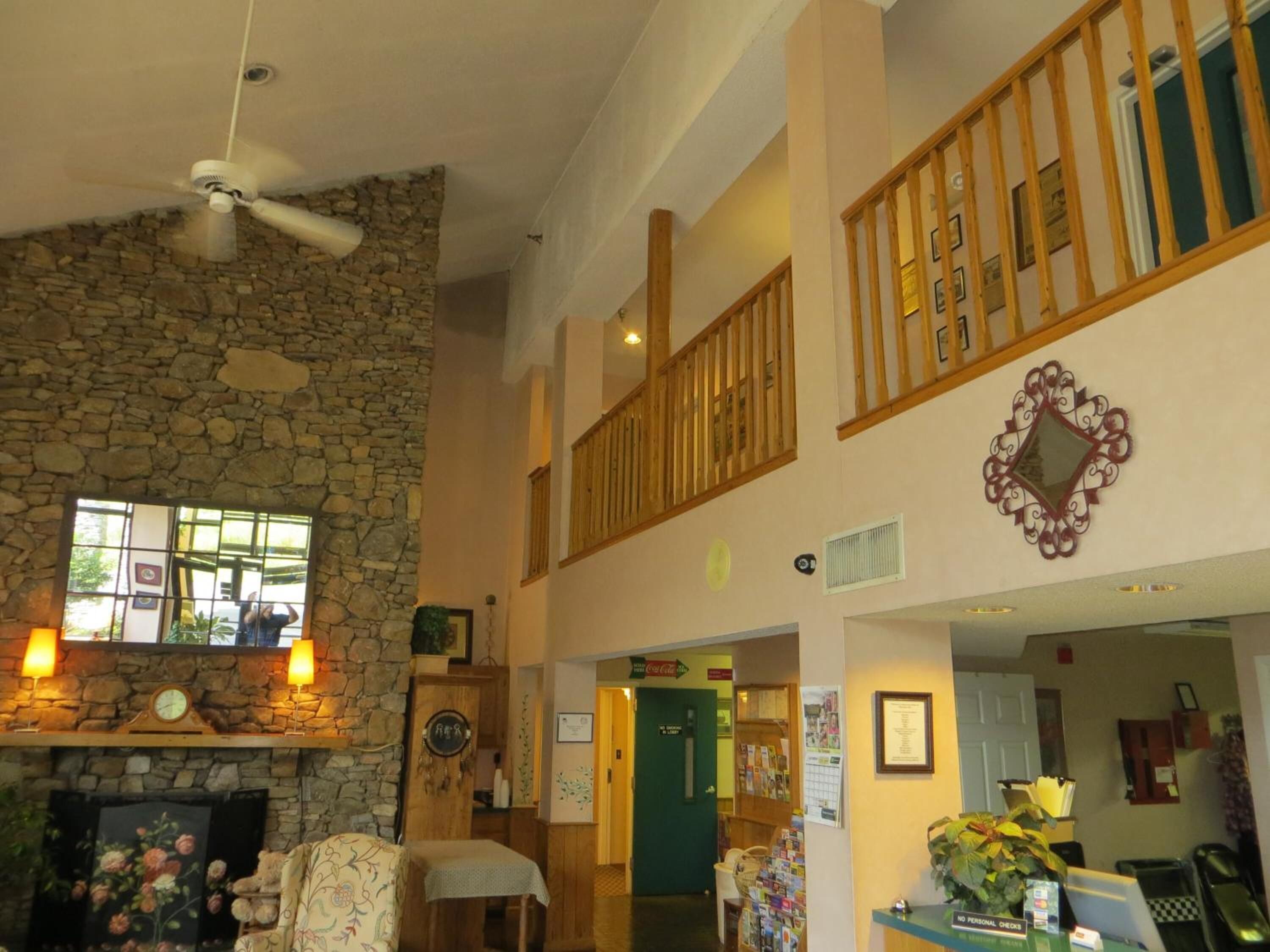 Eine Hotelhalle mit Kamin aus Stein, einer Holztreppe und einer Rezeption.