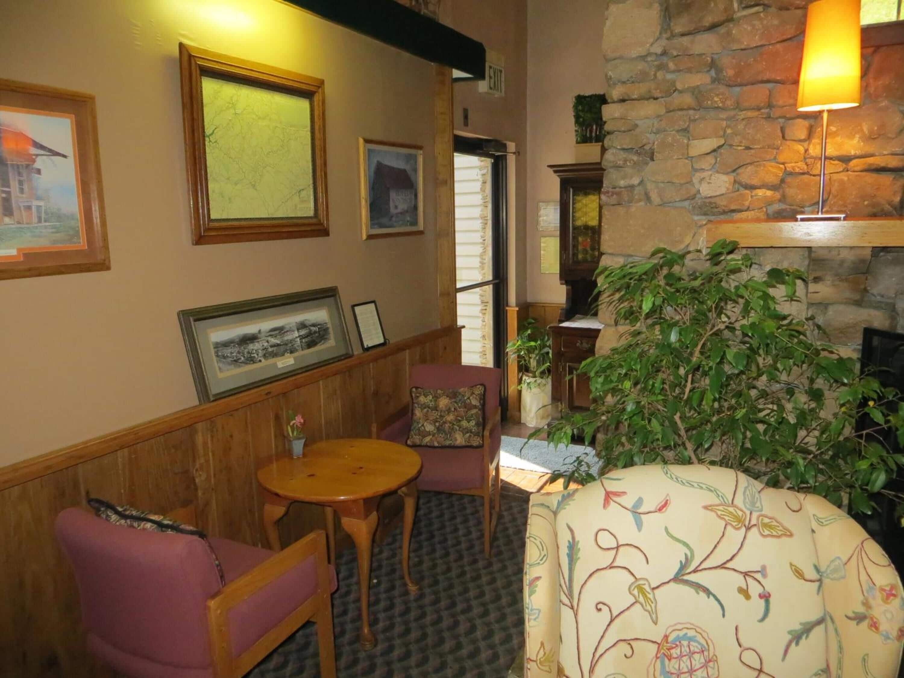 Una habitación acogedora con chimenea de piedra, muebles de madera y cuadros enmarcados en las paredes.