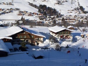 A snow-covered village with traditional wooden houses, a ski slope, and a clear view of the surrounding mountains. - Les Bernards (Praz-sur-Arly)