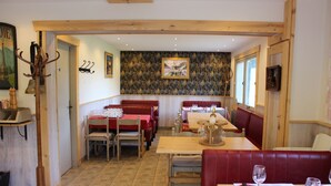 A restaurant interior with wooden beams, red booths, and a patterned wallpaper wall. - Les Bernards (Praz-sur-Arly)