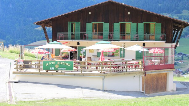A wooden building with a balcony and outdoor seating area, labeled "Le Petit Bernard Bar - Restaurant". - Les Bernards (Praz-sur-Arly)
