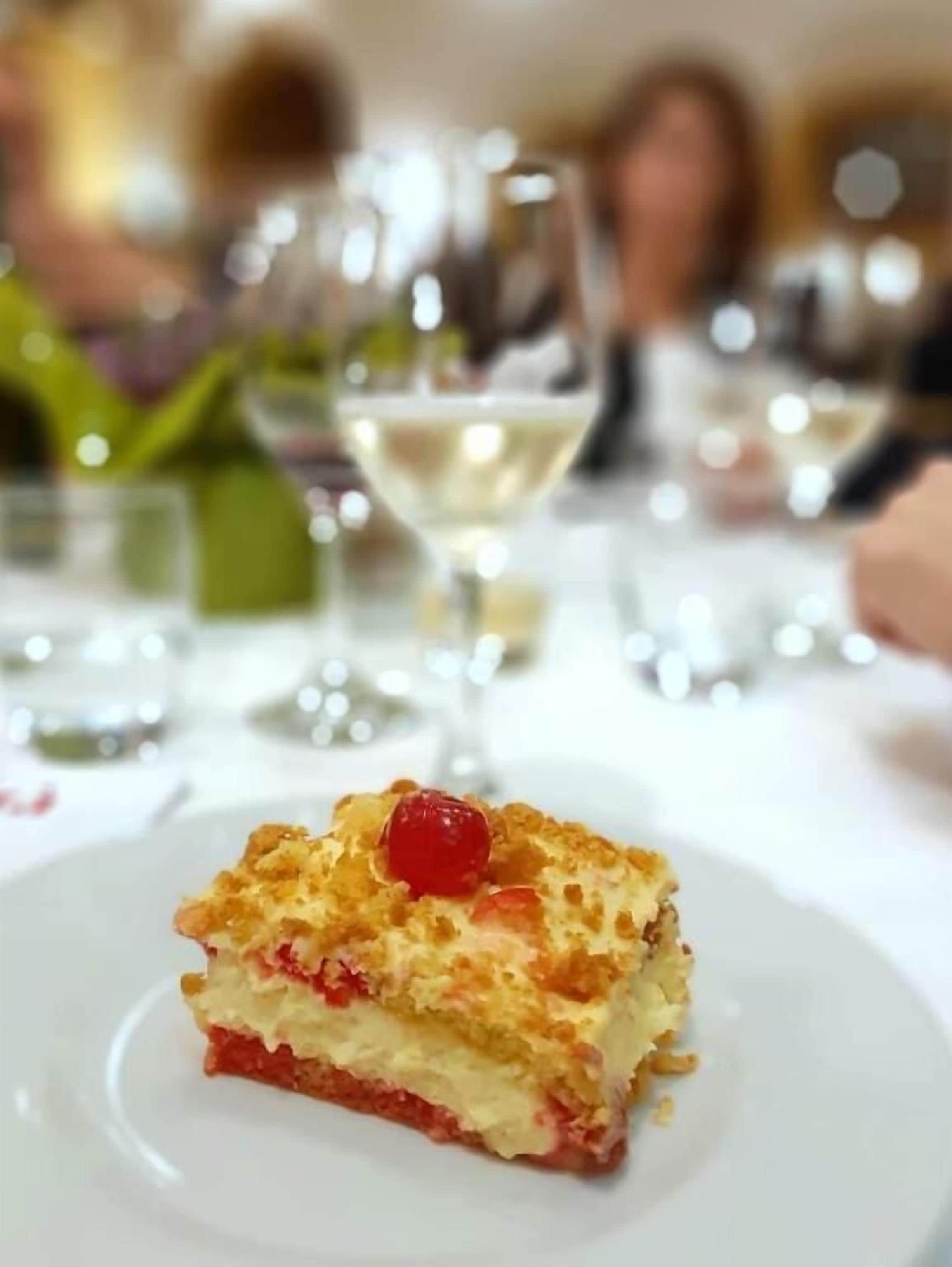 Un postre en un plato con un fondo desenfocado de personas y vasos.