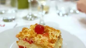 Un postre en un plato con un fondo desenfocado de personas y vasos.