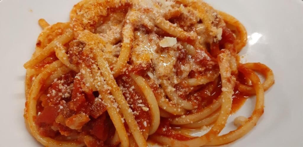 A plate of spaghetti with tomato sauce and grated cheese.