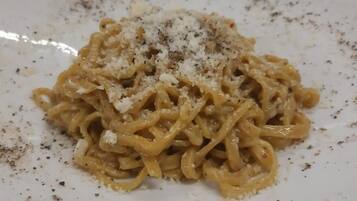 Um prato de massa com molho cremoso e queijo ralado por cima.