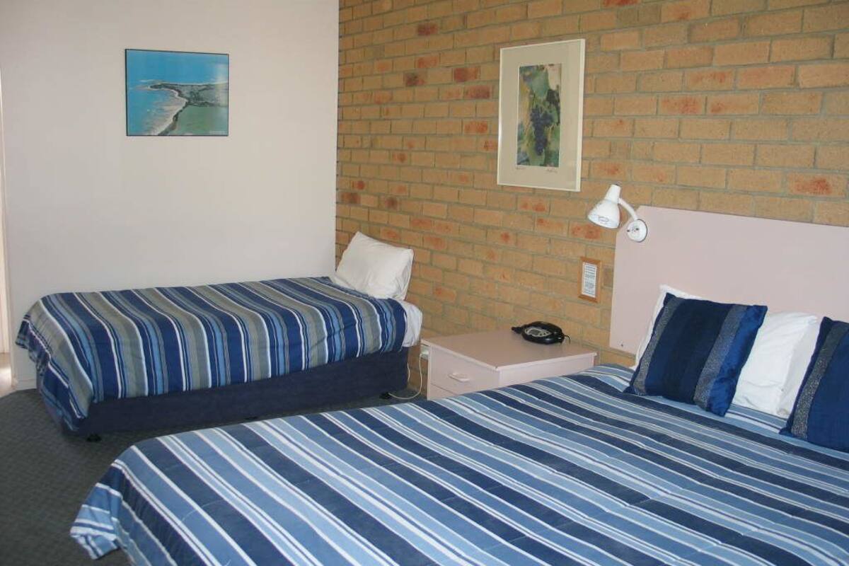 A hotel room with two beds, a brick wall, and artwork on the walls.